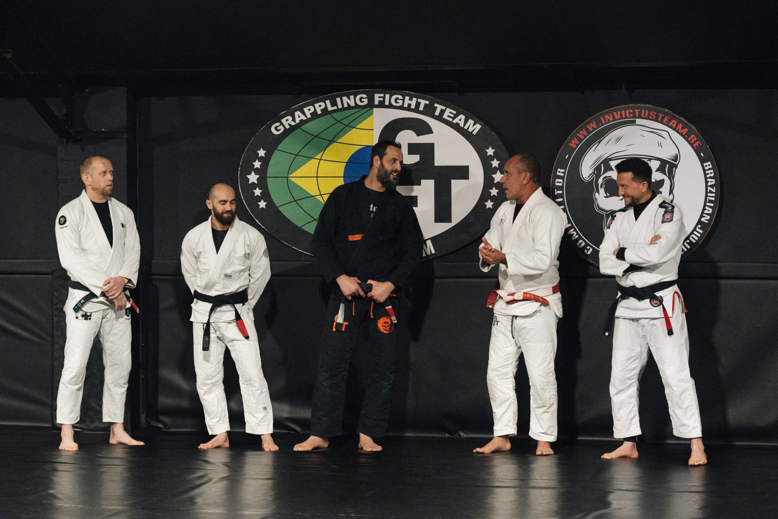 Les coachs Invictus réunis devant les logos Grappling Fight Team, échangeant avant un cours