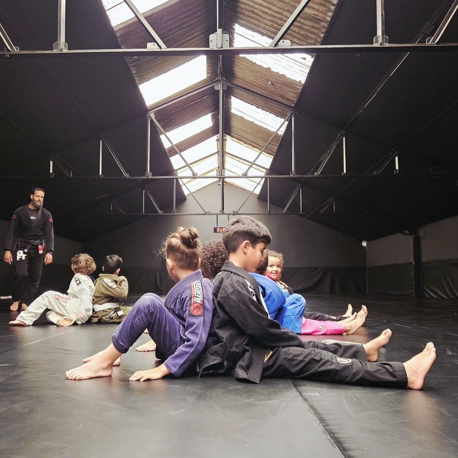 Élèves assis sur le tatami avant l'exercice, sous la supervision du coach